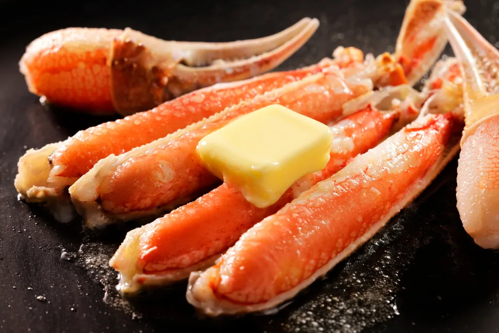 Snow Crab legs cooking on a hot griddle with butter.